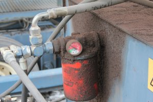 Cette photo représente un système de filtration basse pression sur le retour d’une unité hydraulique dont le manomètre différentiel est dans la zone rouge. Une partie importante de l’huile passe donc par le By-Pass de l’unité de filtration ce qui signifie qu’elle n’est filtrée qu’en partie. Si on ne remplace pas rapidement la cartouche filtrante,  la crépine d’aspiration de la pompe va se boucher et engendrer de la cavitation. Dans ce cas-ci, c’est le seul filtre sur les circuits hydrauliques, les particules non-filtrées vont assurément endommager les vérins, les valves, les moteurs ainsi que la pompe elle-même.